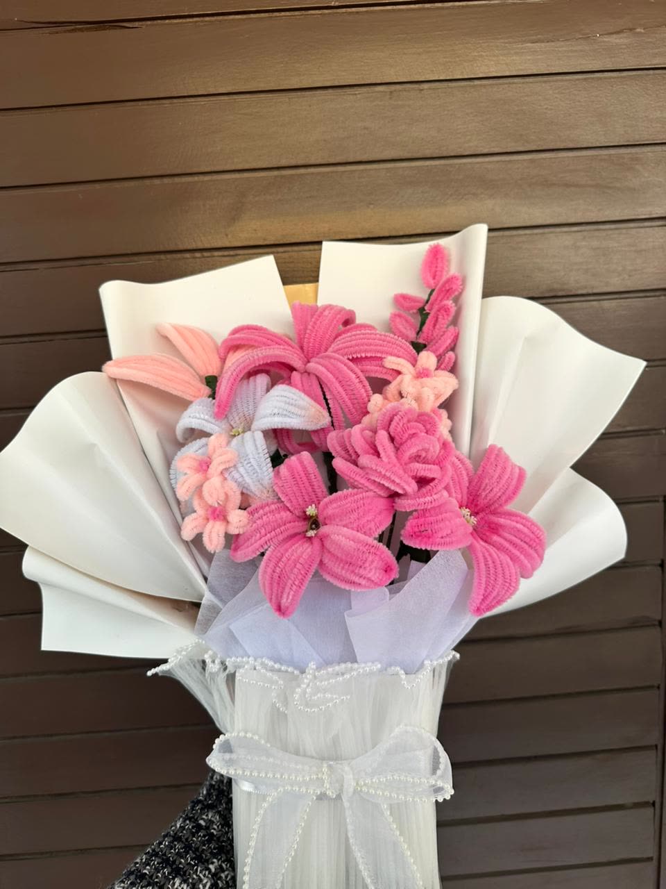 A handmade tofha bouquet of pink flowers wrapped in tissue